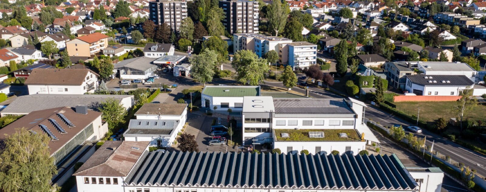 Luftaufnahme des Fleiner Büroparks: mehrere flache Gewerbebauten mit Solardach am Ortsrand von Flein