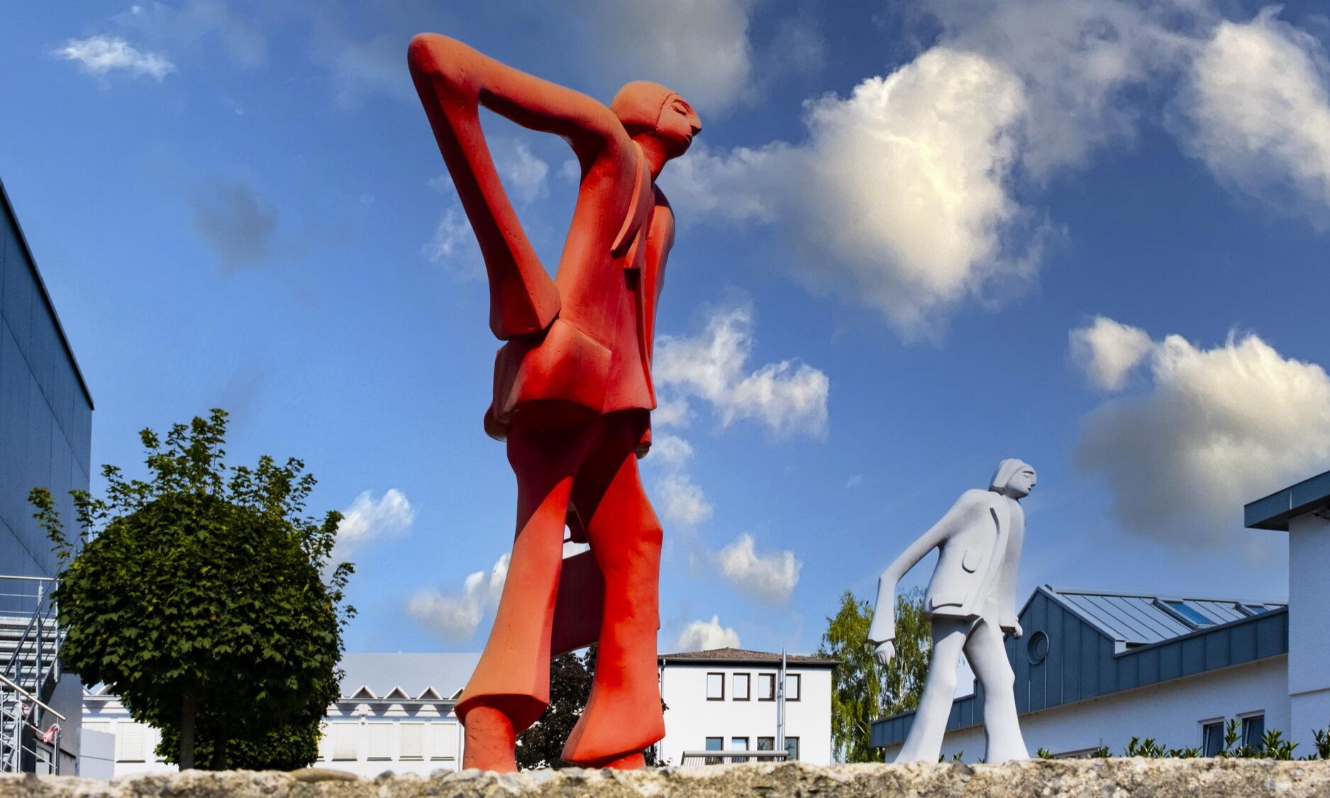 Zwei überlebensgroße Figurenskulpturen in Rot und Weiß vor den Gebäuden des Fleiner Büroparks